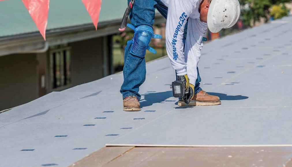 Man standing on roof doing repairs.