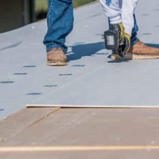 View of man drilling on a roof.