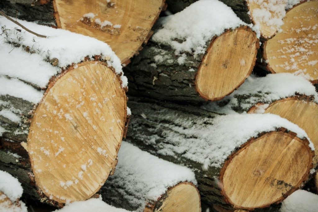 Close-up picture of a stack of lumber with snow on it, representing the affects of weather on building materials shortages.