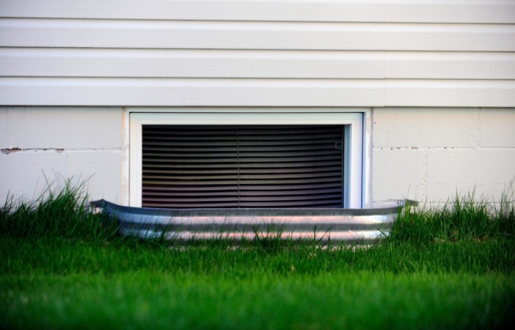 A picture of egress windows with green grass surrounding the window.