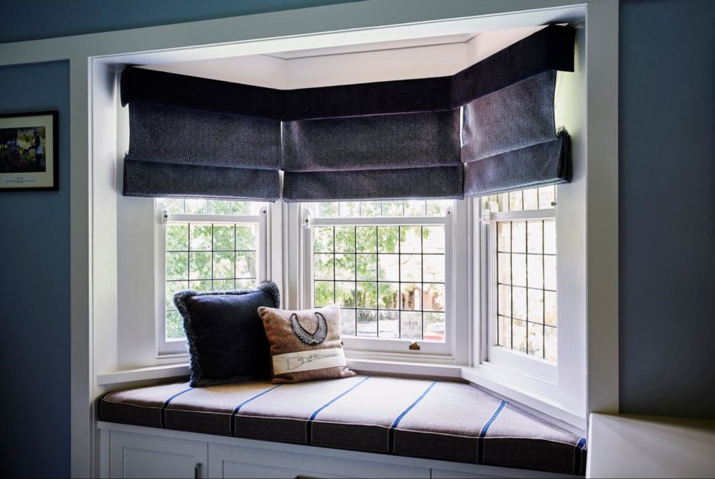 An inside picture of bay windows and a reading nook with two pillows nestled on the seating area.