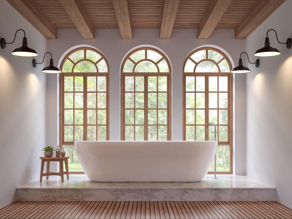 A picture of a bathroom with arched windows, wooden exterior, and a bathroom.