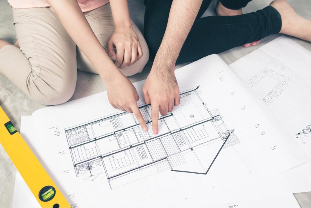 A picture of a young couple looking at a home renovation blueprint.