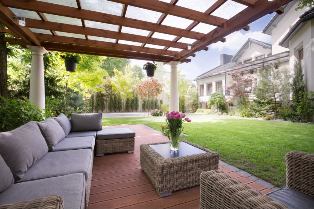 A picture of a floating deck with a grey sofa and pink roses in a vase on a table. 