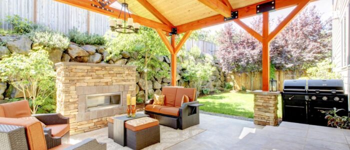 Covered deck with a stone fireplace and outdoor patio furniture.