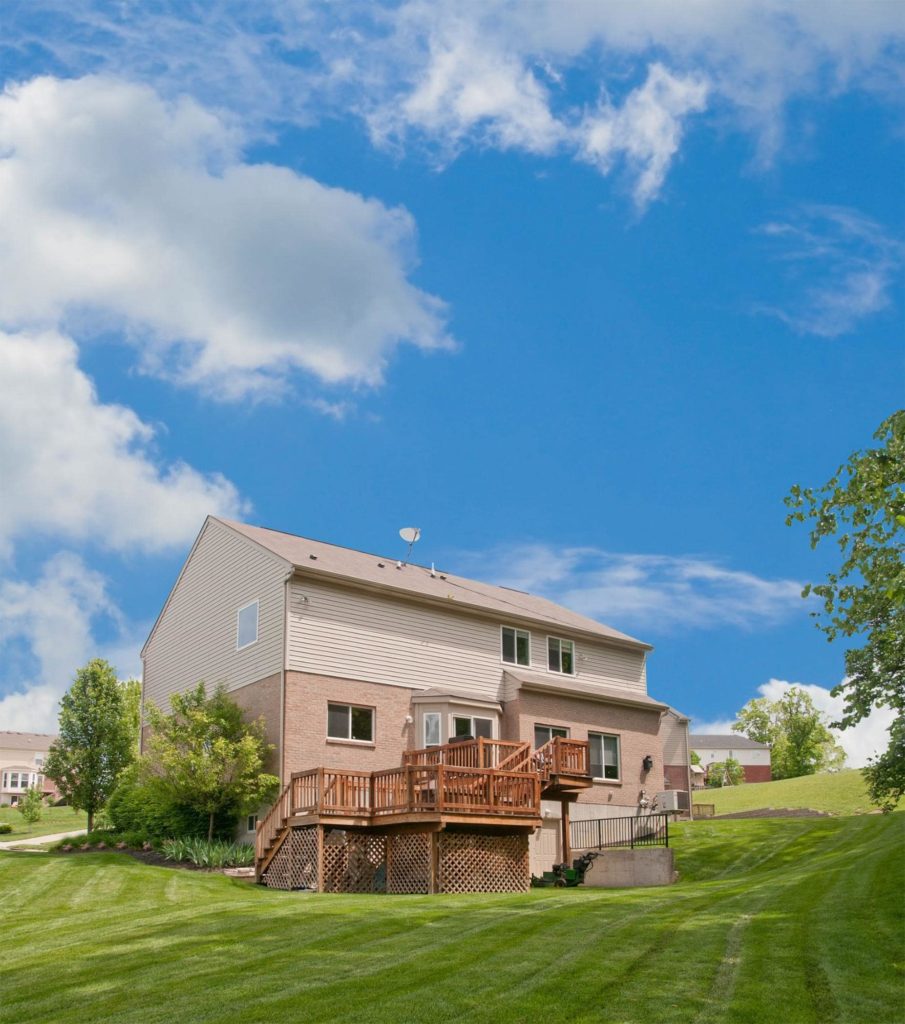 A picture of a two-story deck with a large backyard on a sunny day.