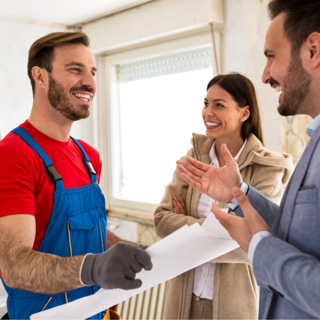 Contractor showing a happy couple the blueprints for a home remodel.