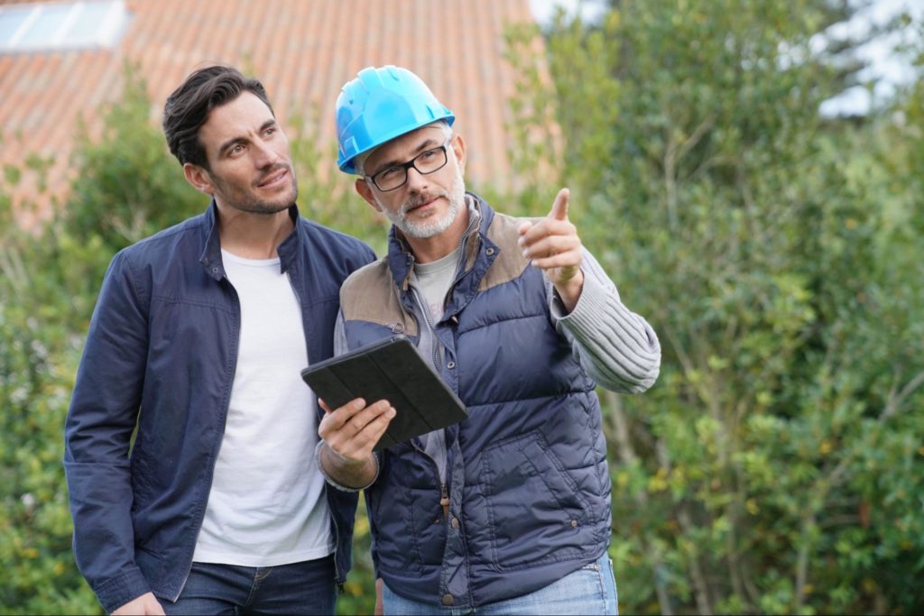 A picture of an investor and a real estate contractor holding an iPad and pointing to a remodel project.