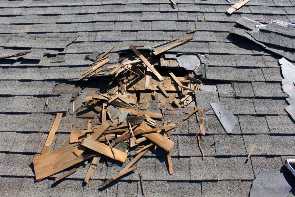 A picture of a roof with broken wood shingles.