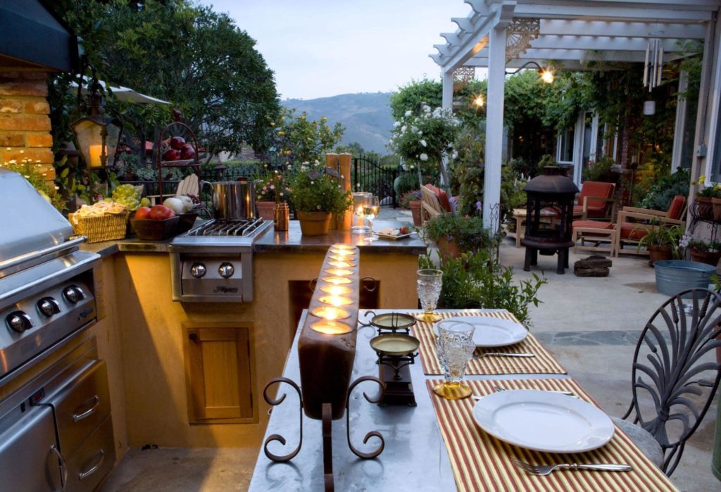 A picture of an outdoor patio with a grill, candles, and a fully functional kitchen.