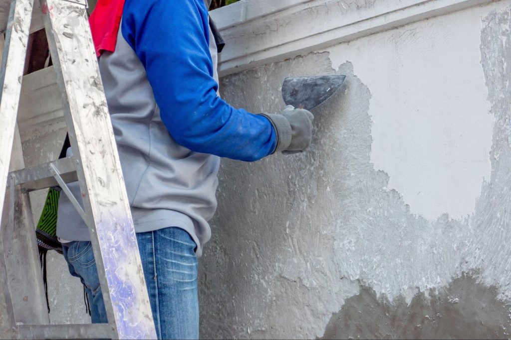 A picture of a contractor completing the stucco remediation process on the outside of a home.