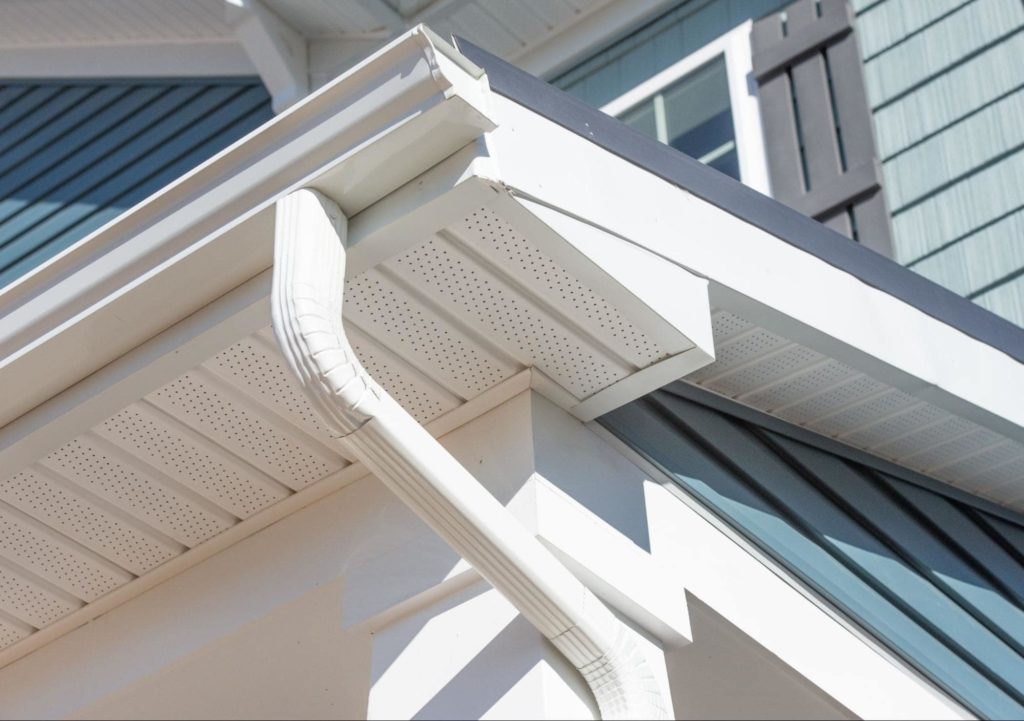 A picture of white gutters teal with siding behind it.