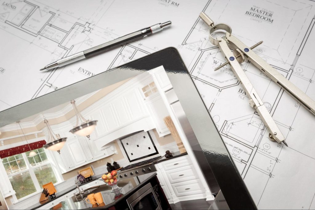 An iPad with a picture of a modern kitchen on it and kitchen design blueprints behind the iPad.