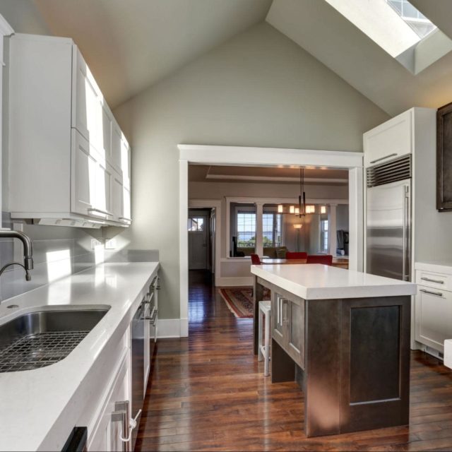 A modern kitchen with white cabinets and hardwood floors.