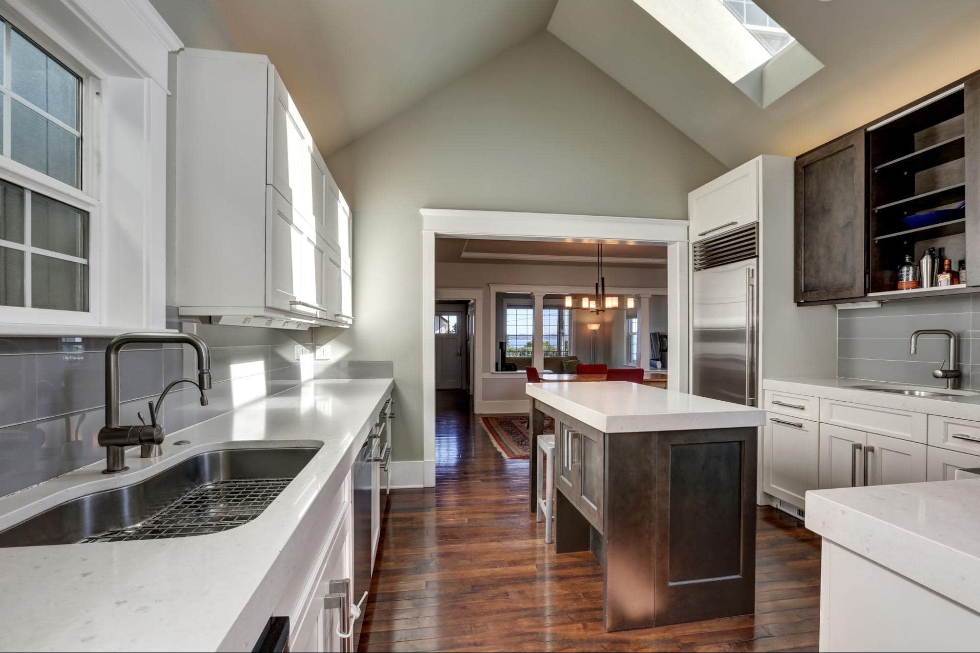 A modern kitchen with white cabinets and hardwood floors.