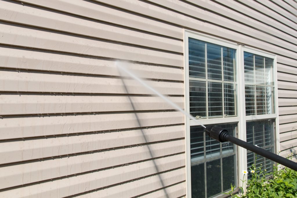Someone pressure washing the siding on a house.