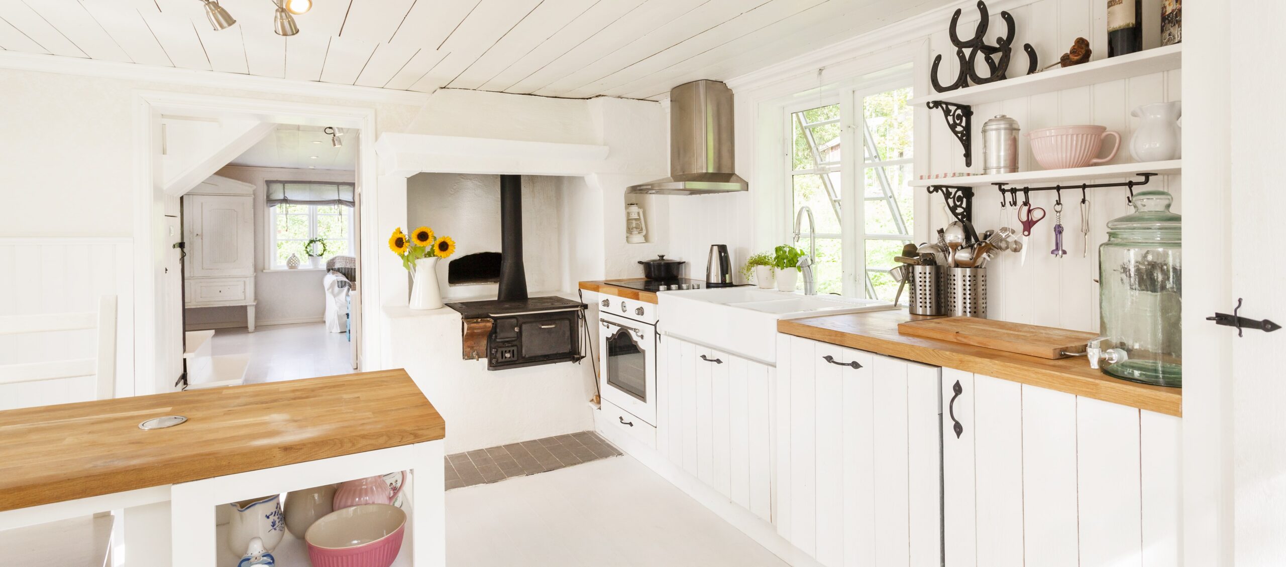 A rustic kitchen design idea with white wood cabinets and wood countertops.