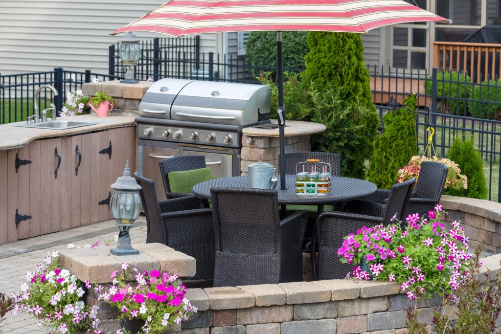 A stone patio with an outdoor kitchen that has a grill and sink.