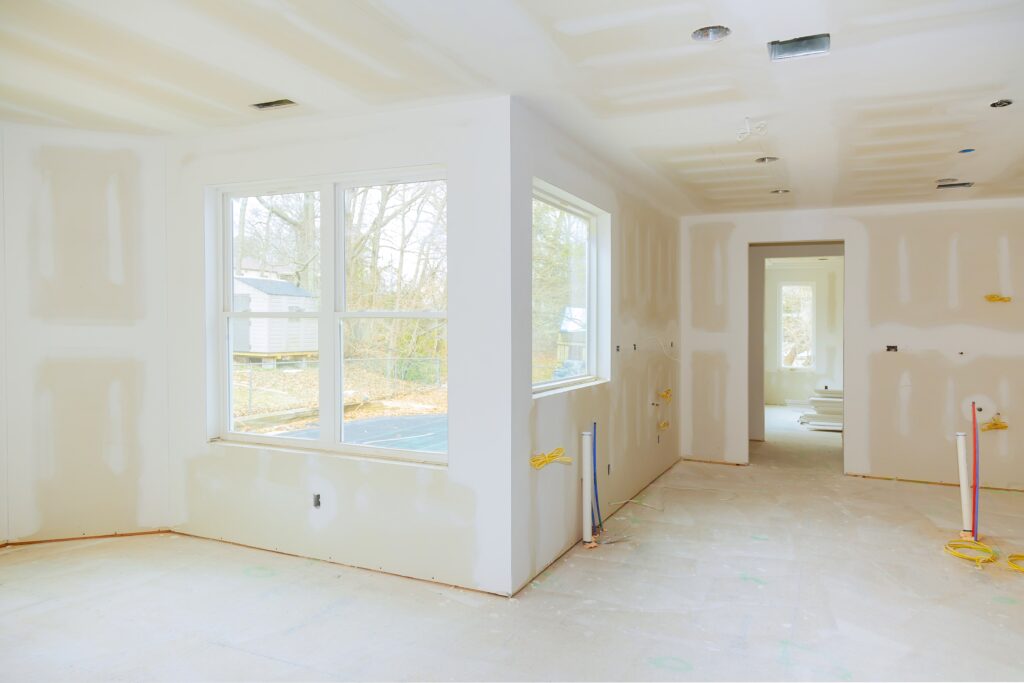 The inside view of a home being remodeled, showing sheetrock, electrical wires, and plumbing lines.